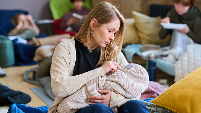Mãe com bebé com outros refugiados